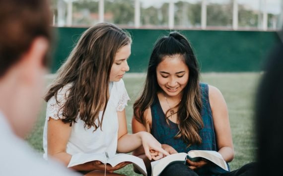 Small group sitting together reading a book