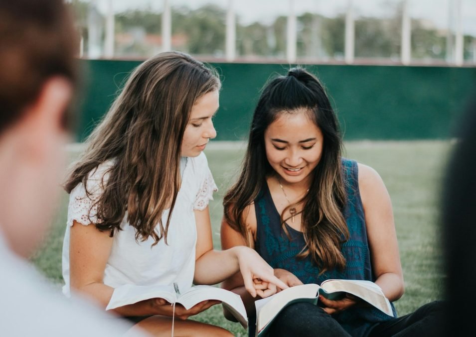 Small group sitting together reading a book