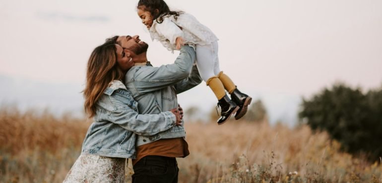 Parents lifting a child in a field