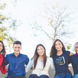 Group of friends sitting on a bench near trees