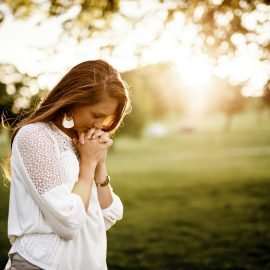 Woman praying beside a tree